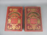 une paire de livres anciens rouges et dorés posés sur une surface blanche