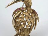 a close up of a gold bird brooch with pink and blue stones