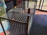 a cage that is sitting on the floor next to a surfboard