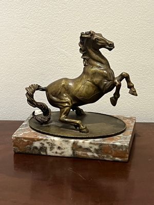 statue en bronze représentant un cheval, posée sur un socle en marbre, elle-même posée sur une table