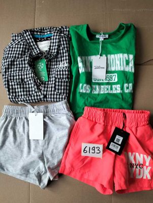 three pairs of shorts and a t - shirt are on a cardboard box