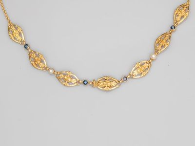 a gold necklace with blue stones and gold leaves