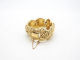 a close up of a gold bracelet on a white surface
