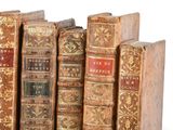 several old books are lined up in a row on a white surface