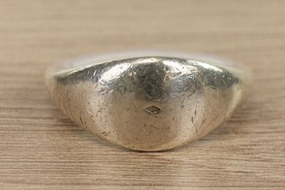 silver ring with a heart shaped design on top of a wooden surface
