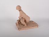 une petite statue représentant un garçon assis sur un rocher