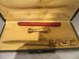 un stylo rouge et un couteau doré dans un étui