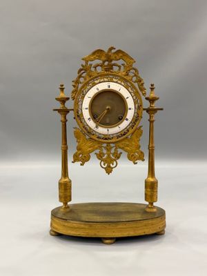une horloge dorée posée sur un socle, sur fond blanc