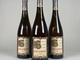 trois bouteilles de vin posées sur une table blanche