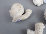 three white sculptures of heads and hands on a gray surface