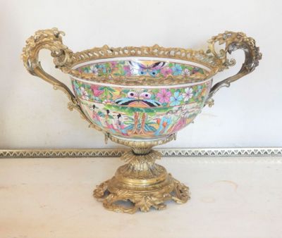 a gold vase with a bird on it on a table