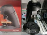 une cafetière noire posée sur un plan de travail, à côté d'une boîte de café