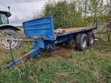 a blue trailer with a tractor behind it in a field