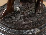 a bronze statue of a woman sitting on a rock