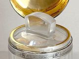 a glass container with a gold lid sitting on a white surface