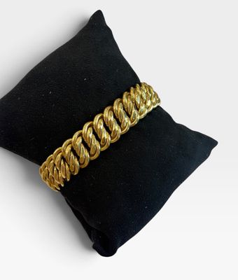 gros plan d'un bracelet en chaîne en or sur un oreiller