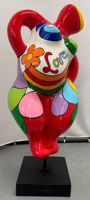 un vase coloré posé sur un socle noir, avec un mur blanc en arrière-plan