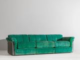 a green couch sitting on top of a white floor next to a wall