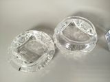 two clear glass ashtrays sitting on top of a white counter