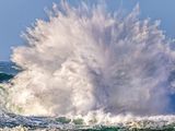 waves crashing on the shore of a beach with a person on a surfboard in the foreground