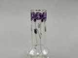 un vase en verre contenant des fleurs violettes, posé sur une table
