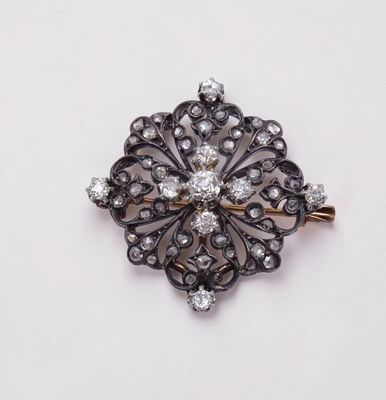 un gros plan d'une broche en diamant posée sur une surface blanche