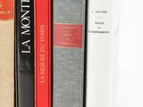 several books are stacked on top of each other on a white surface
