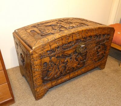 an old wooden chest sitting on top of a carpeted floor next to a chair