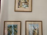 three paintings hanging on a wall above a toilet in a bathroom
