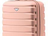 La valise rose repose sur ses roulettes, posée sur une surface blanche.