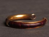 a close up of a gold bracelet with a red stone in the middle