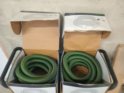 deux boîtes posées par terre, contenant des tuyaux verts