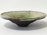 un bol vert bordé de noir sur un fond blanc