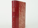 un vieux livre rouge posé sur une surface blanche