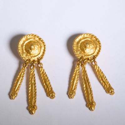 paire de boucles d'oreilles dorées ornées de pompons sur fond blanc