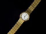 a gold wrist watch with a white face and a chain around it