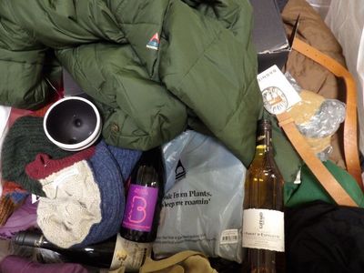a pile of clothing and a bottle of wine on the floor