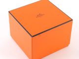 an orange box with a black lid sitting on a white surface