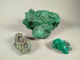 trois morceaux de minéral vert disposés côte à côte sur une surface blanche