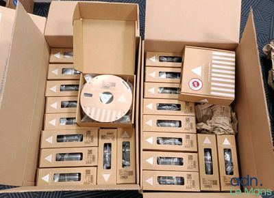 de nombreuses boîtes contenant des appareils électroniques, empilées dans une boîte posée par terre