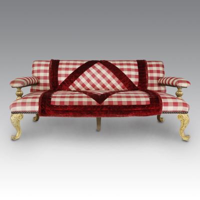 a red and white checkered couch with gold legs and pillows