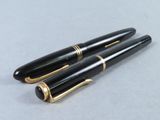 pair of black and gold fountain pens sitting on top of a table