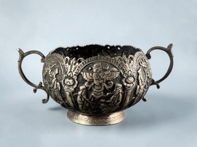 an image of a silver bowl with handles on a blue background