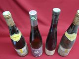 four bottles of wine are lined up on a red cloth