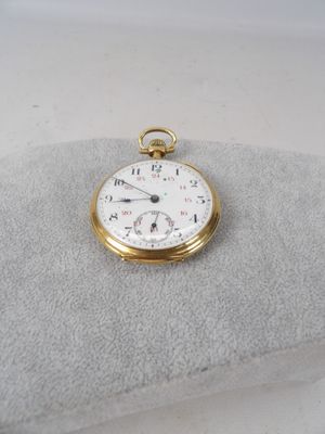une montre de poche en or posée sur un oreiller
