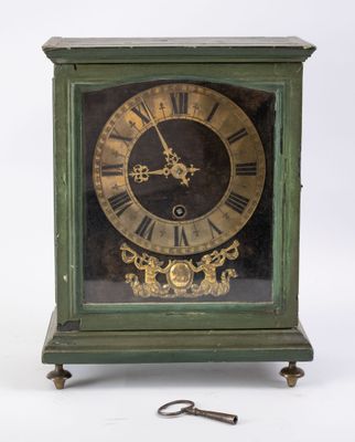 une horloge verte avec un cadran doré et une clé posée devant