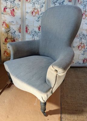 a blue chair that is sitting in front of a wallpapered wall