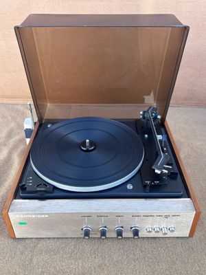 le tourne-disque est posé sur le tapis, près du mur