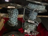 deux bobines de chaîne et une bobine de fil métallique posées sur une table