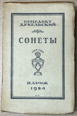 an old book sitting on top of a wooden table next to a cup